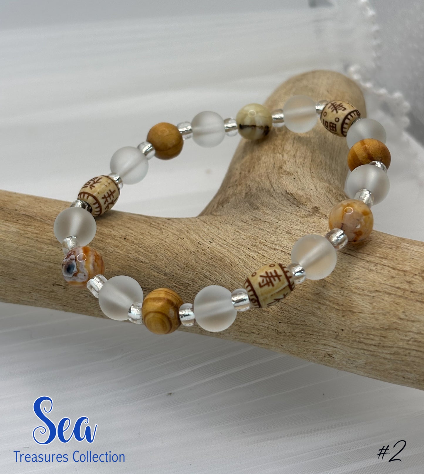 Beaded bracelet with wooden and clear beads on a wooden branch, featuring 'Sea Treasures Collection' branding.