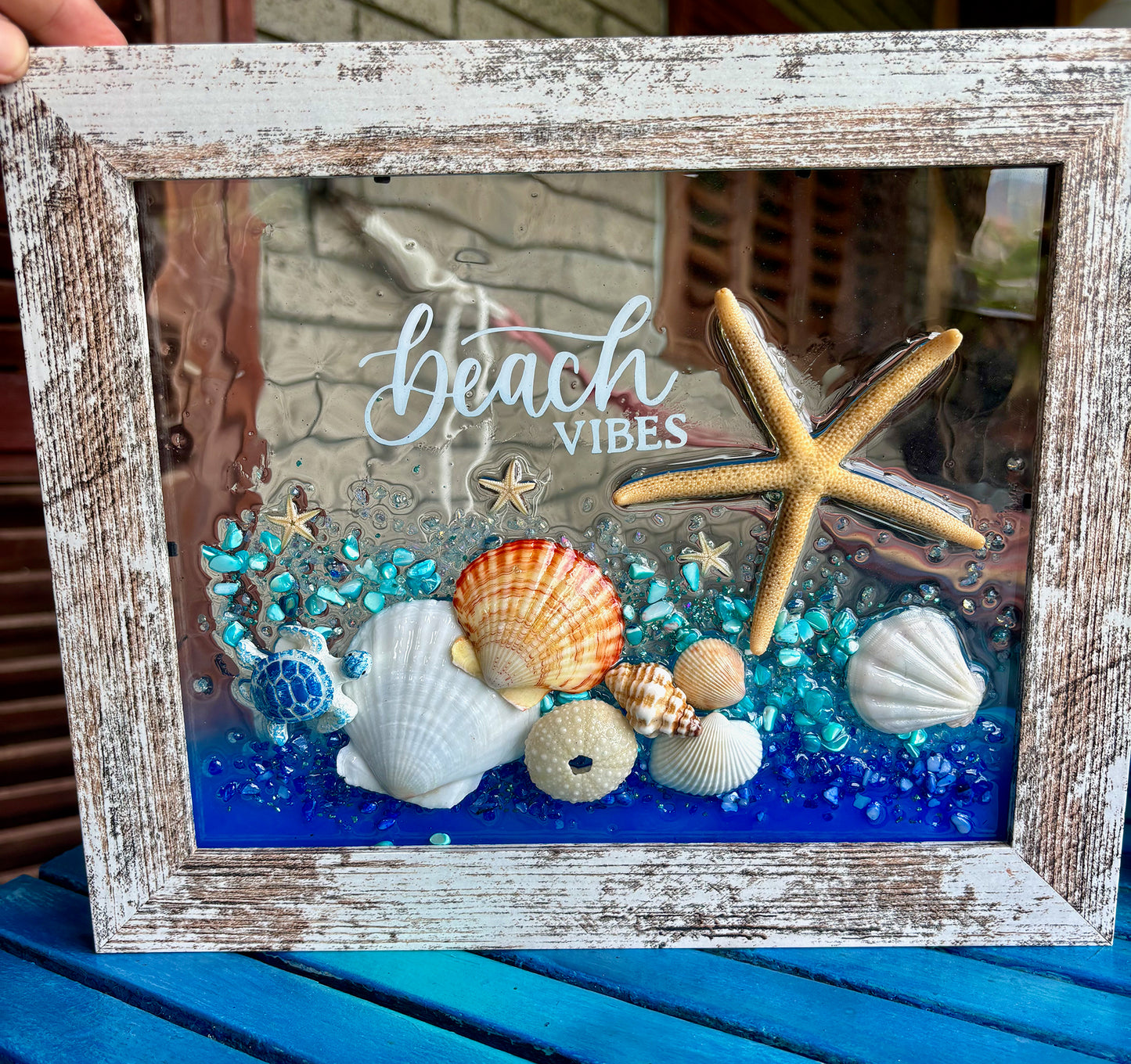Decorative art piece with beach-themed elements including shells, a starfish, and the word 'beach vibes'.