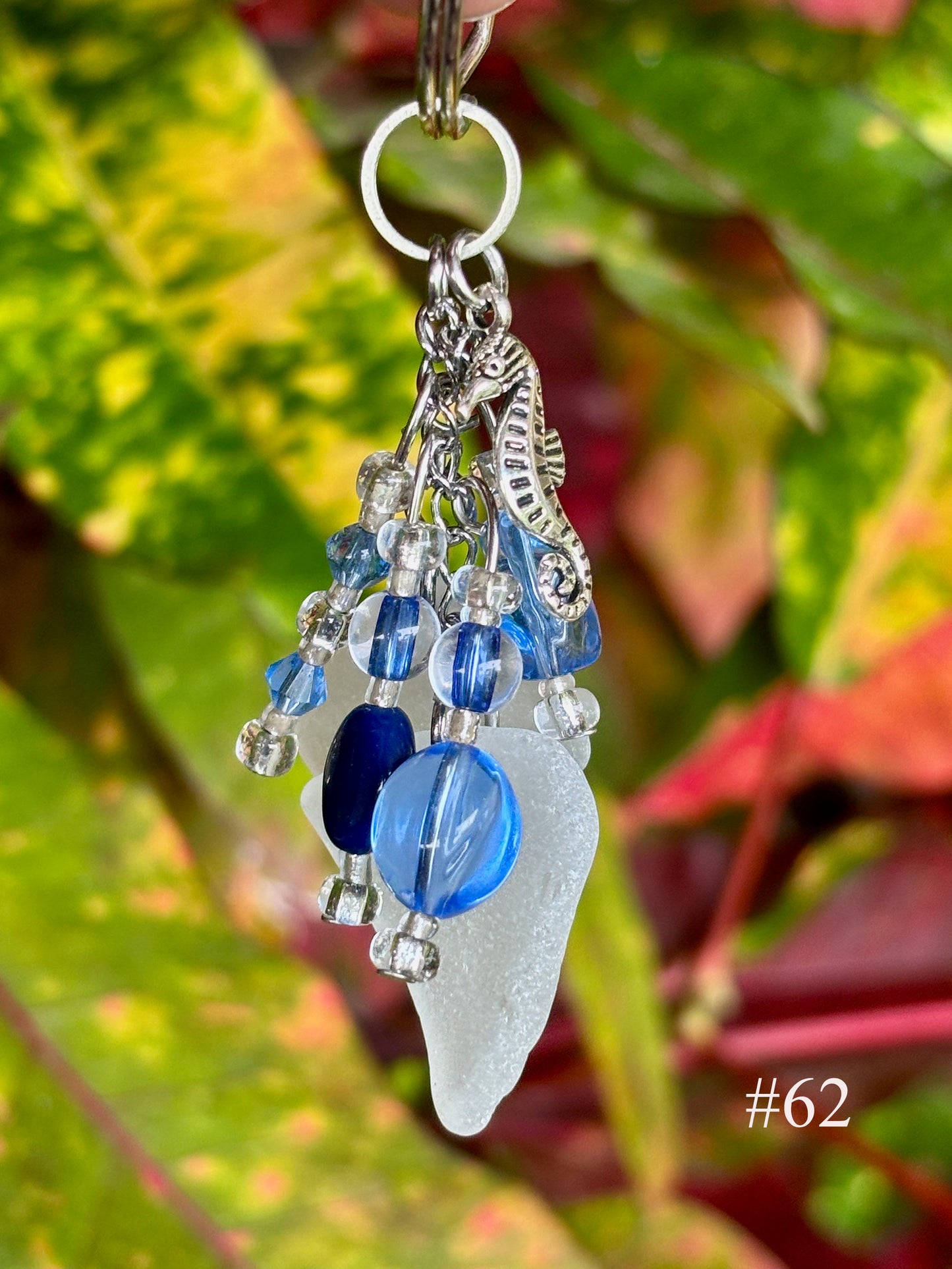 Decorative keychain with blue and silver charms against a leafy background