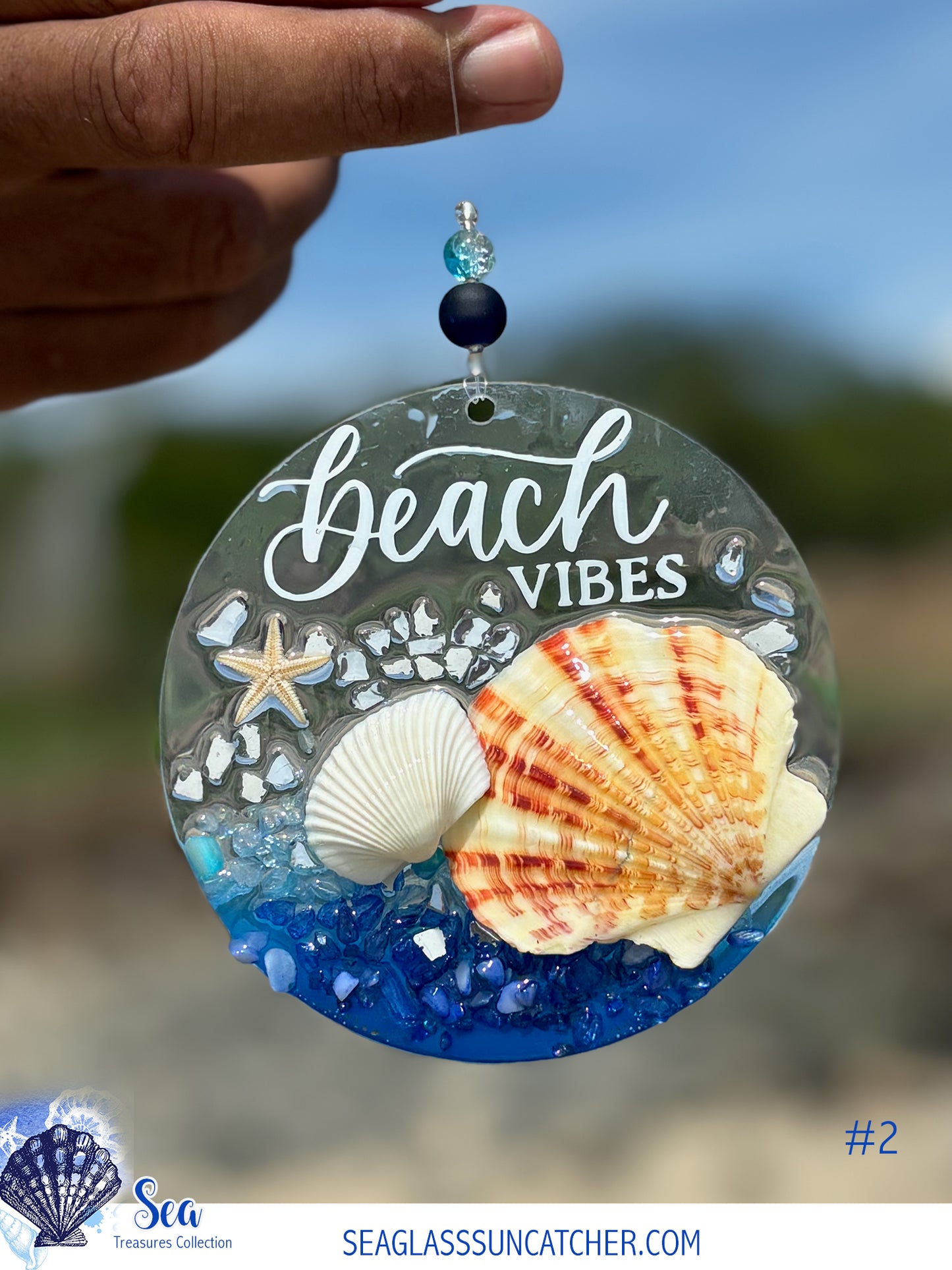 Decorative seaglass suncatcher with 'Beach Vibes' text, shells, and a starfish against a blurred beach background.