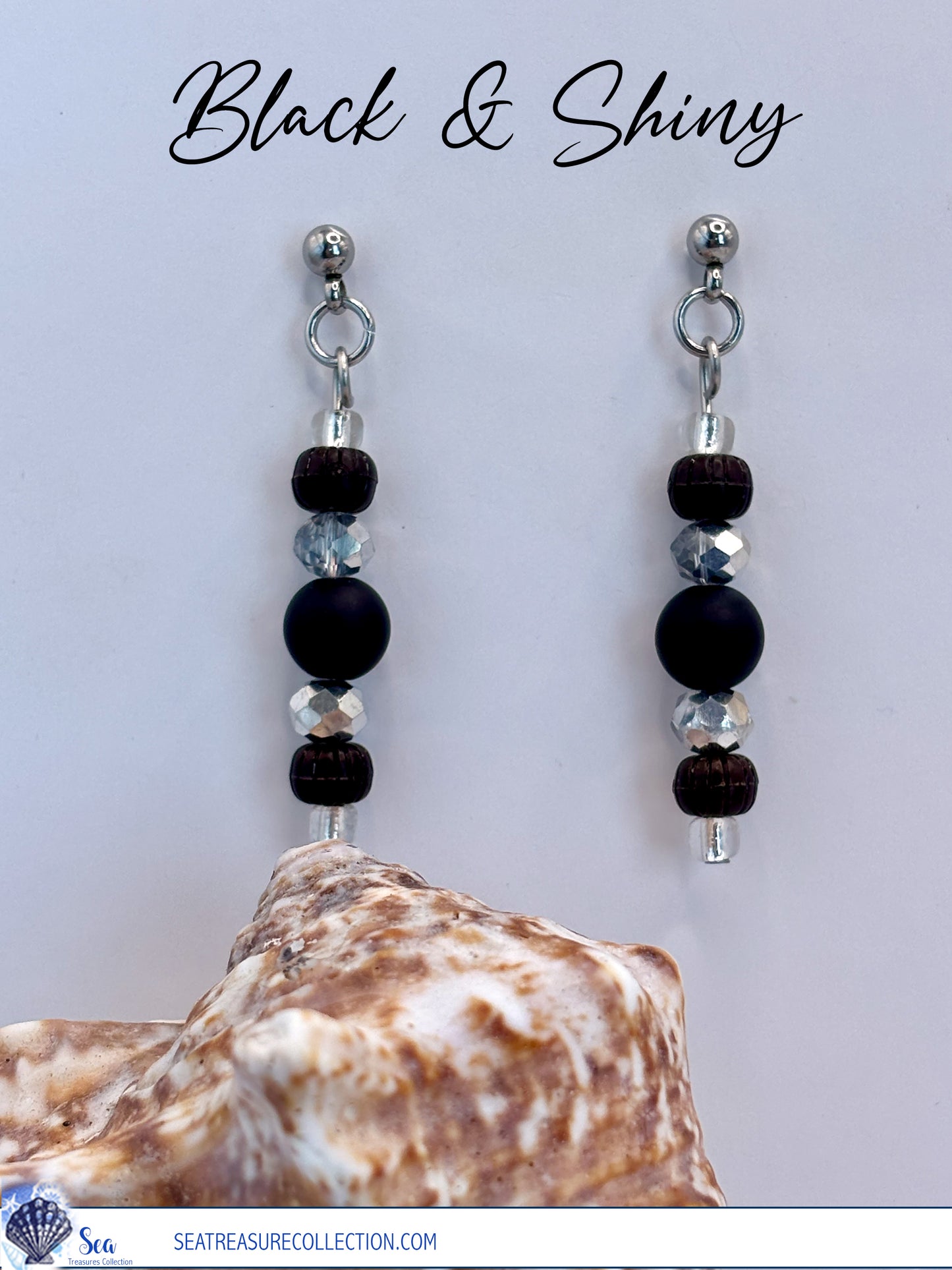 Black and shiny beaded earrings with a shell on a light gray background