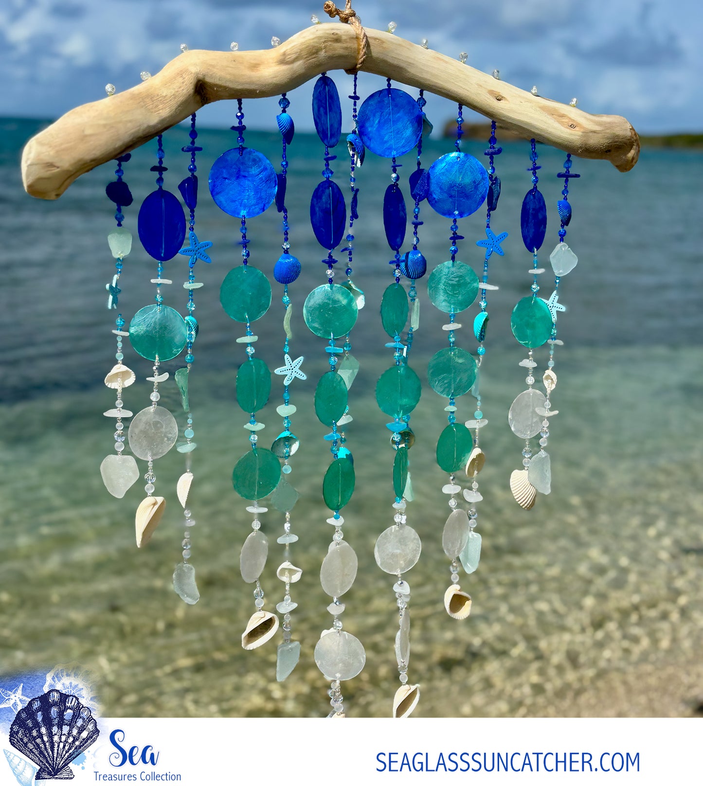 Decorative wind chime with blue and white sea glass, beads and seashells against a beach background.