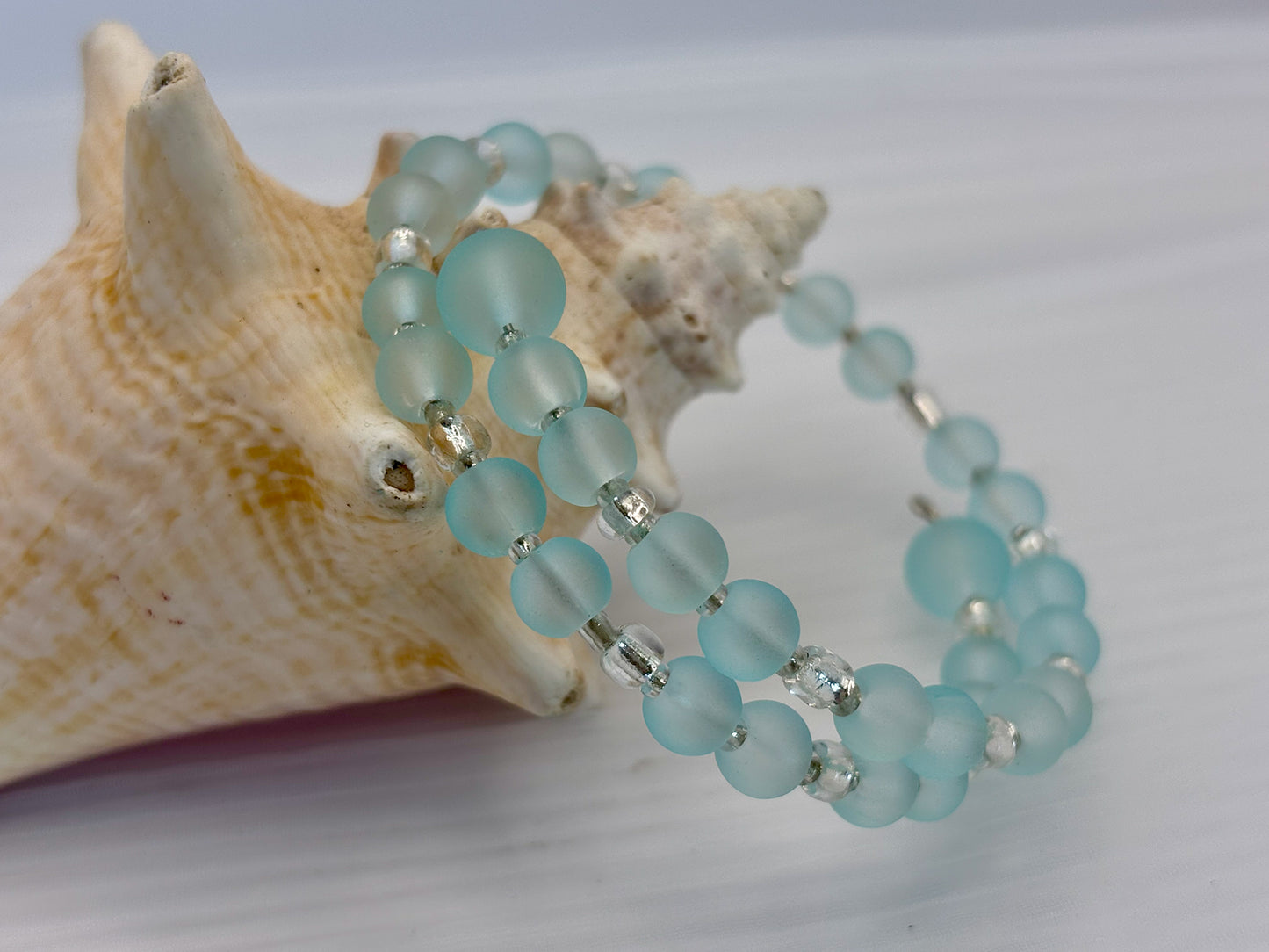 Turquoise beaded bracelet with silver accents on a shell background