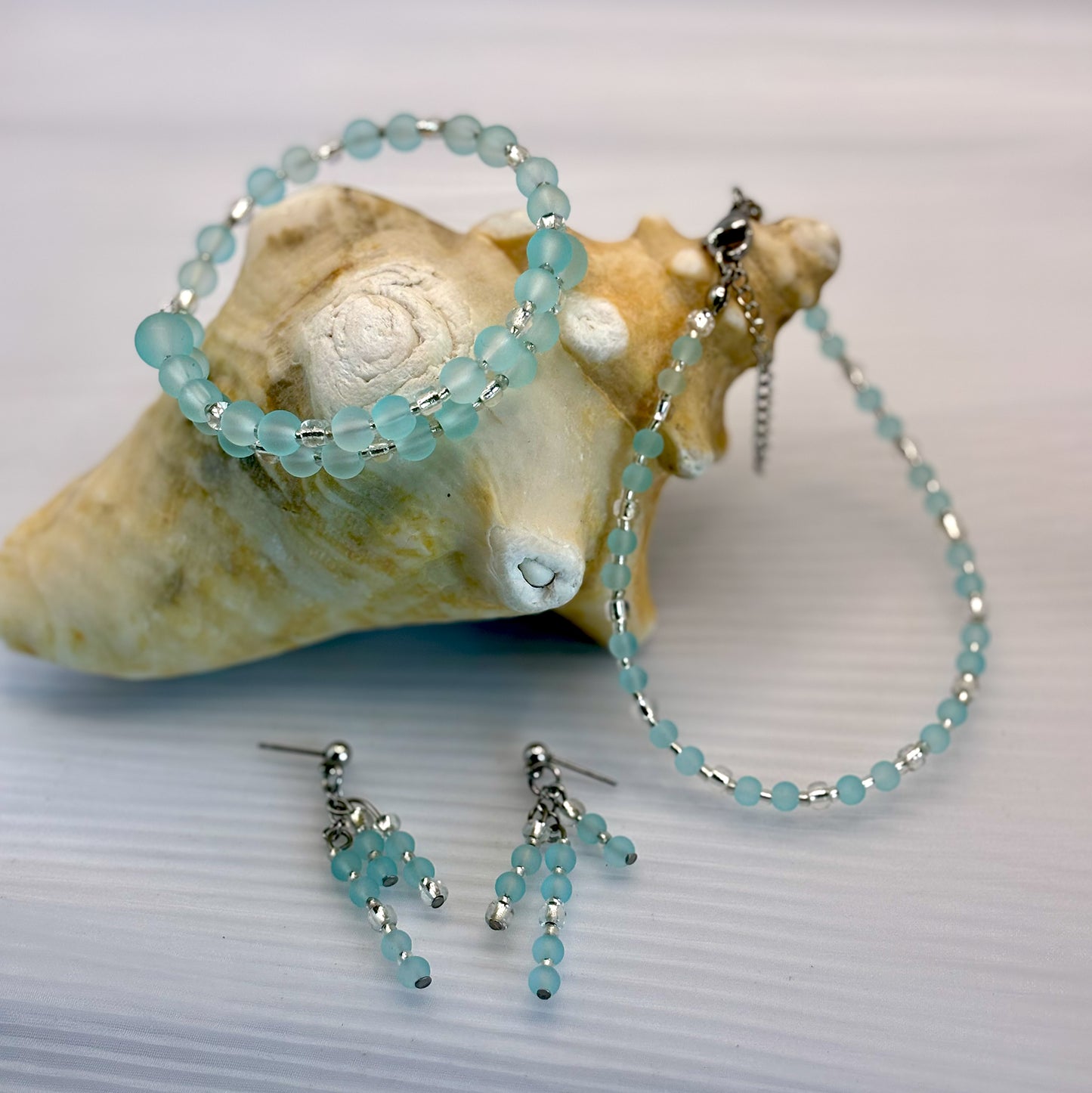 Set of turquoise beaded jewelry including bracelet, anklet and earrings on a shell background