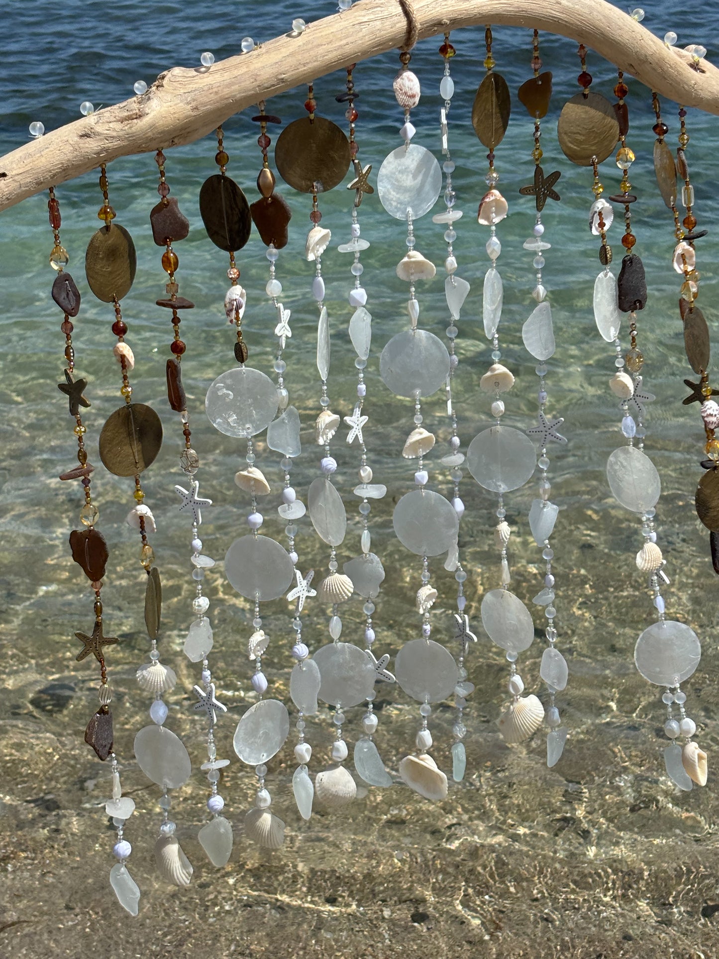 Decorative hanging with seaglass and shells by a body of water