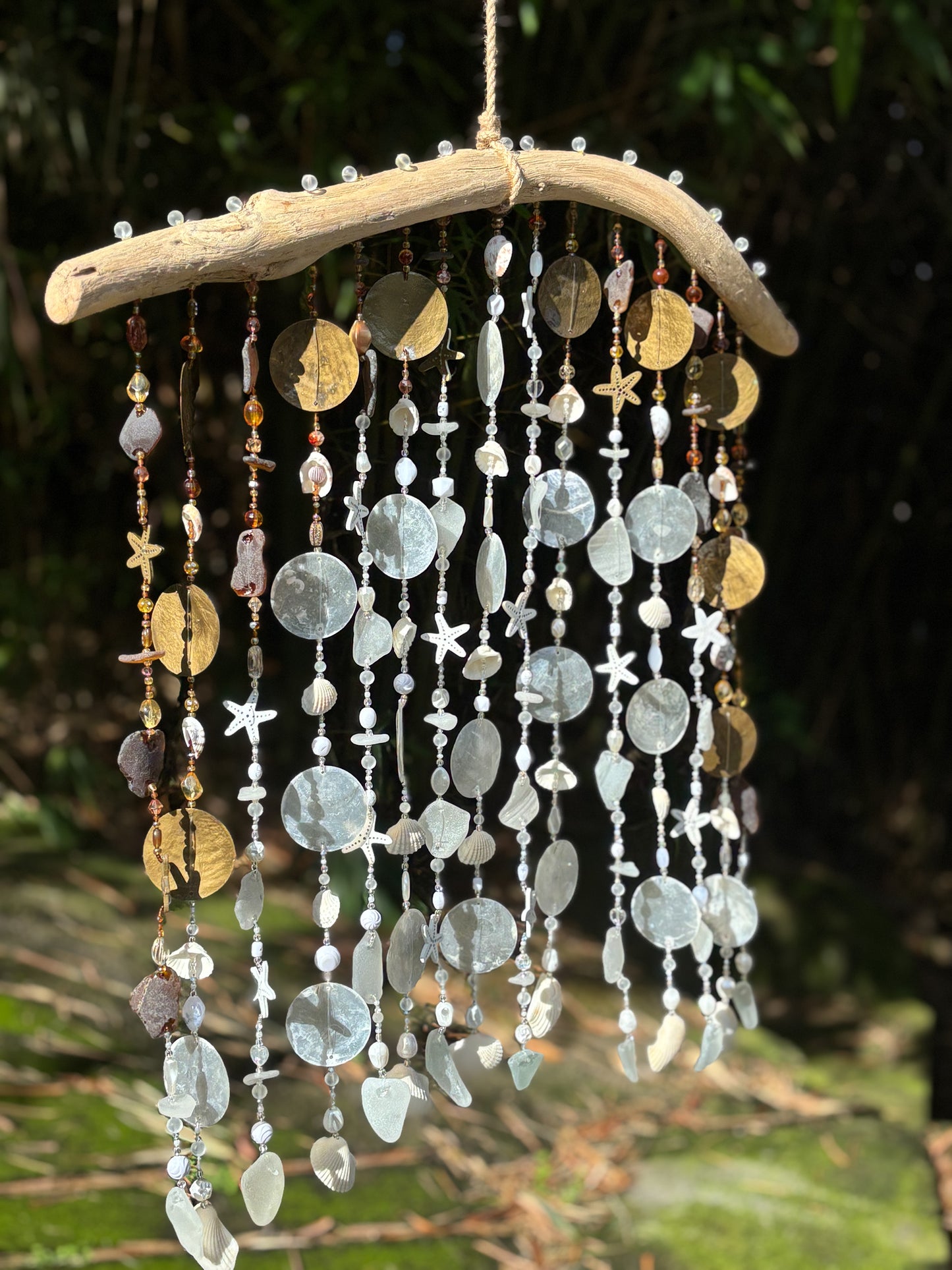 Decorative wind chime with beads and natural elements against a blurred green background
