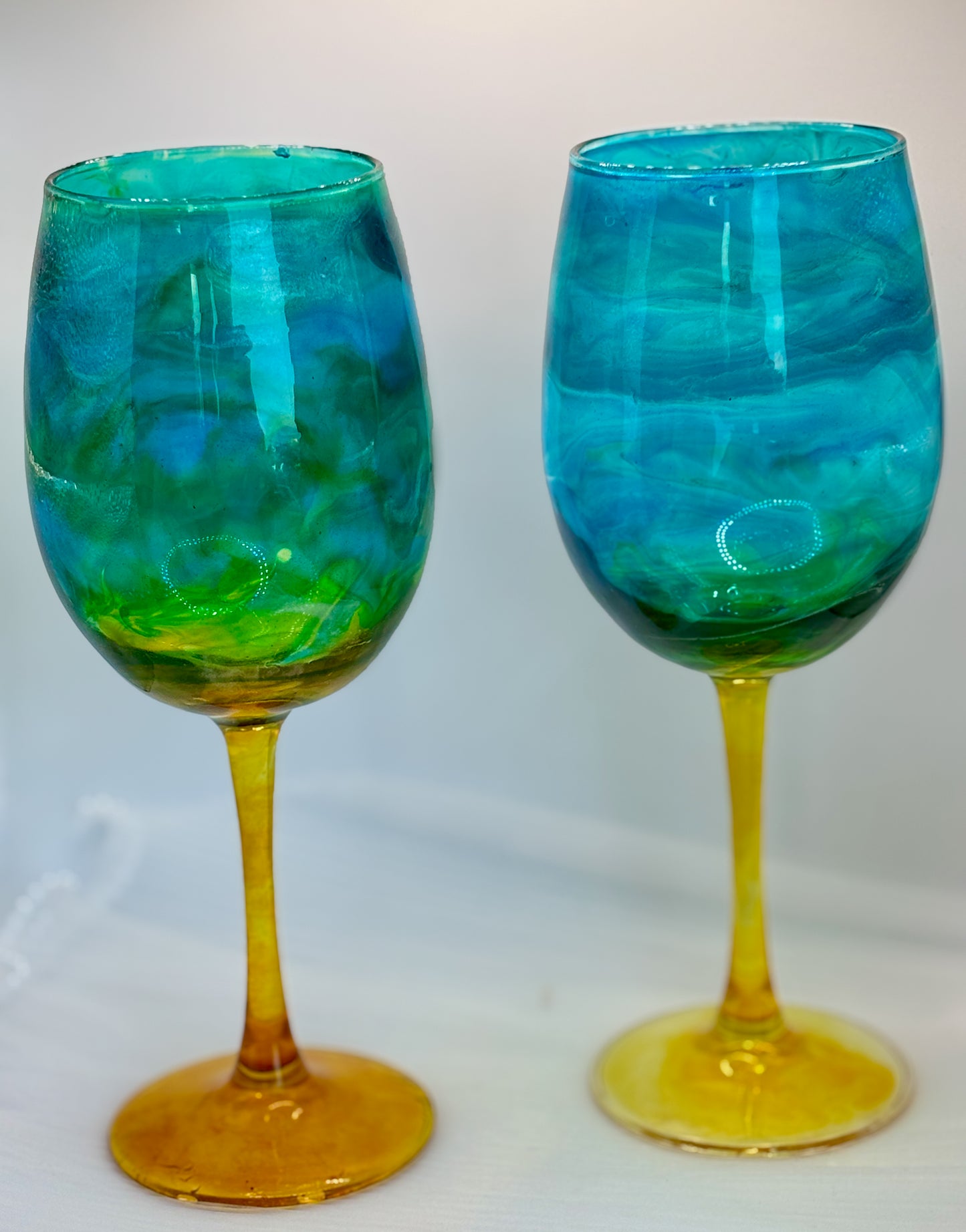 Two turquoise and gold wine glasses on a white background