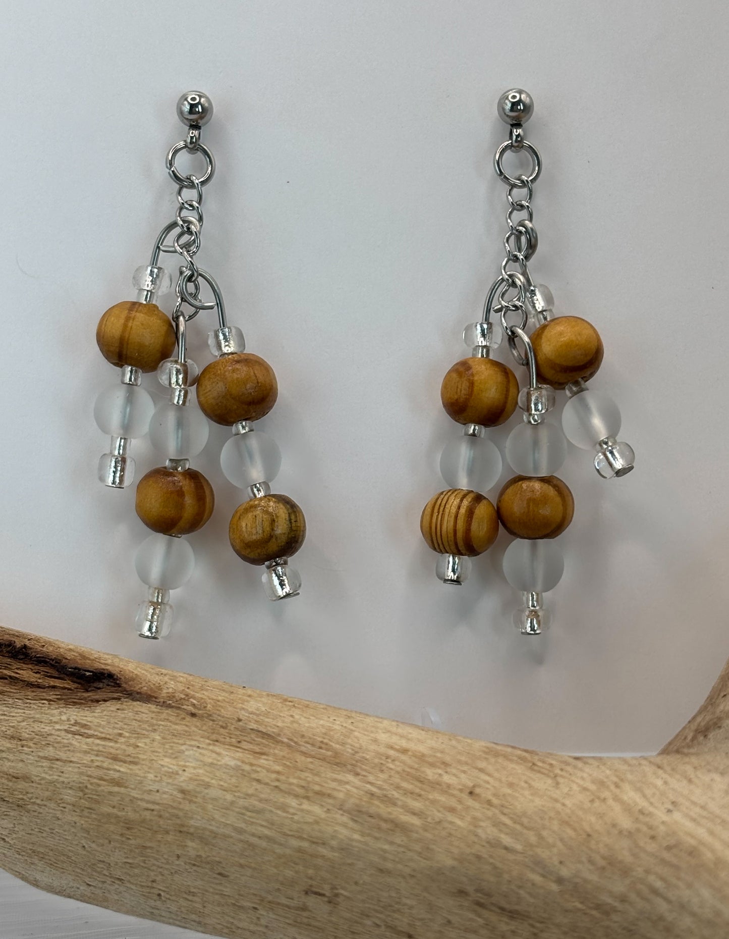 Pair of earrings with wooden beads and clear beads on a white background