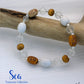 Beaded bracelet with white, brown, and clear beads on a wooden branch with 'Sea Treasures Collection' branding.