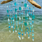 Coastal Wind Chime on driftwood  with turquoise and white beads, shells, sea glass on a beach