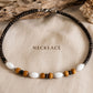 Close-up of the Island Drift handmade necklace with coconut beads, wood beads, white accents and stainless steel details.