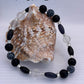 Bracelet with black and clear beads on a shell against a light gray background
