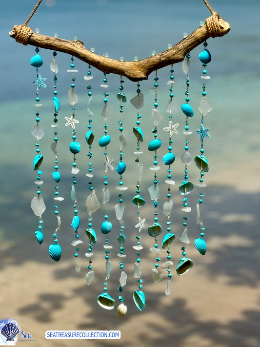 Decorative sea glass and sea shell wind chime with turquoise beads and shells against a blurred beach background