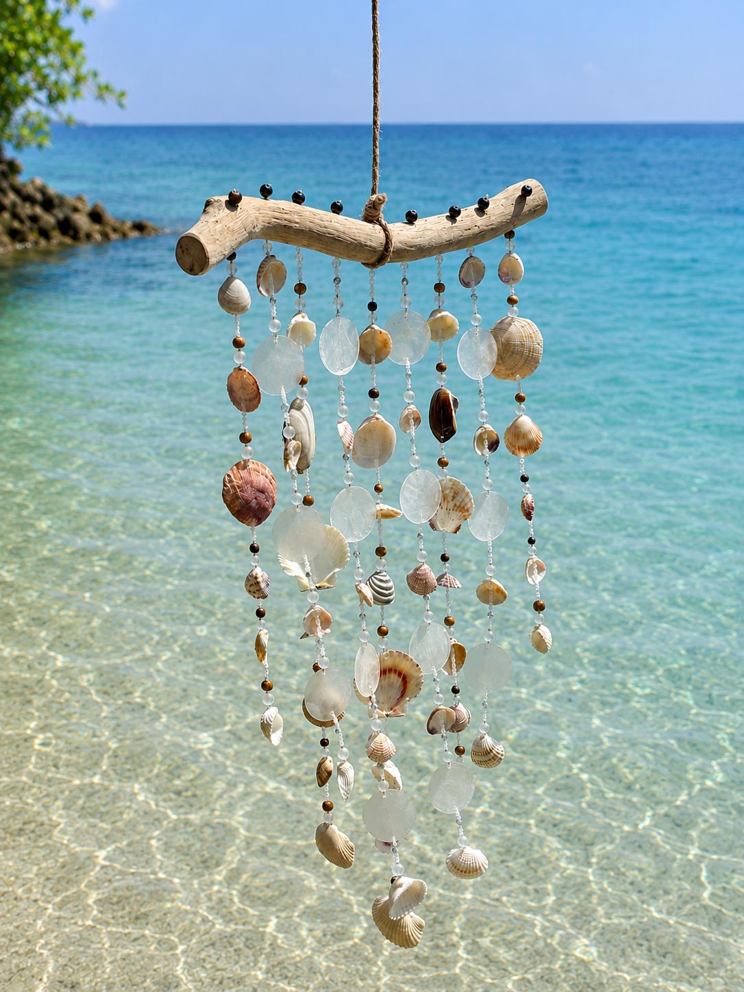 Front view of a handcrafted driftwood wind chime with natural seashells and glass accents.