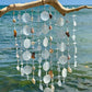Decorative hanging mobile with seashells and beads against a beach background