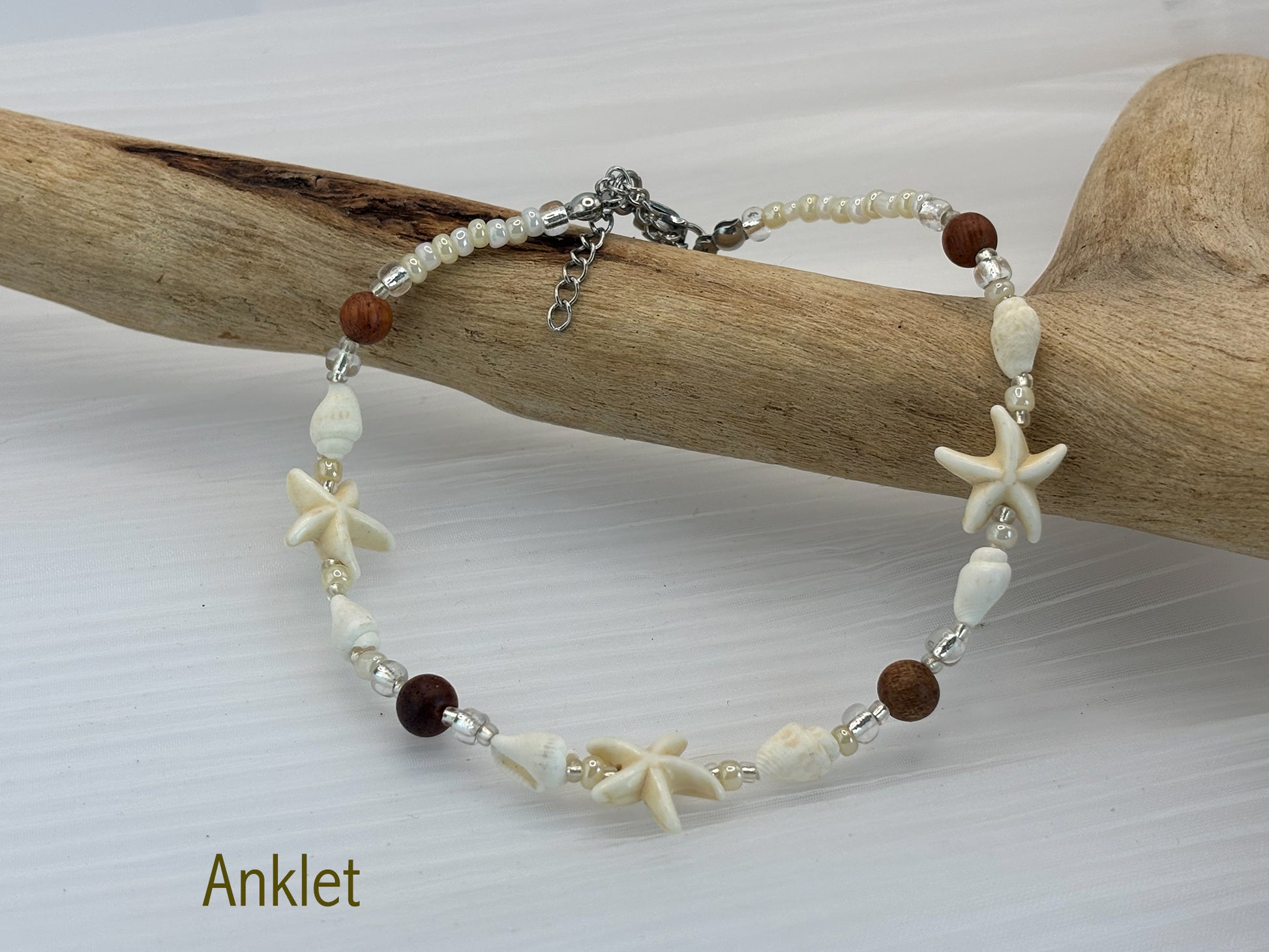 Beaded anklet with starfish and shell designs on a wooden branch