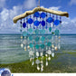 Seaglass sun catcher with blue and white beads against a beach backdrop