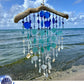 Seaglass suncatcher with blue and white beads hanging against a beach backdrop.i