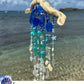 Decorative wind chime with blue and white sea glass against a beach background