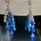 Blue beaded earrings with silver hooks on a dark background