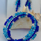 Blue beaded bracelet and earrings on a white background with shells.