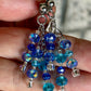 Blue beaded earrings held between fingers with a blurred background