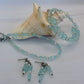 Turquoise beaded anklet, bracelet and earrings with a shell on a light background