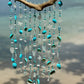 Sea Glass wind chime with turquoise beads and shells against a blurred natural background