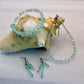 Set of turquoise beaded jewelry including bracelet, anklet and earrings on a shell background