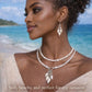 Woman wearing a necklace and earrings with a beach background, featuring 'Whispering Shells' jewelry.