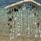 Decorative hanging mobile with shells, sea glass and beads by a body of water