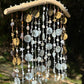 Decorative wind chime with beads and natural elements against a blurred green background