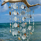 Decorative wind chime with natural elements against a blue sky and ocean background
