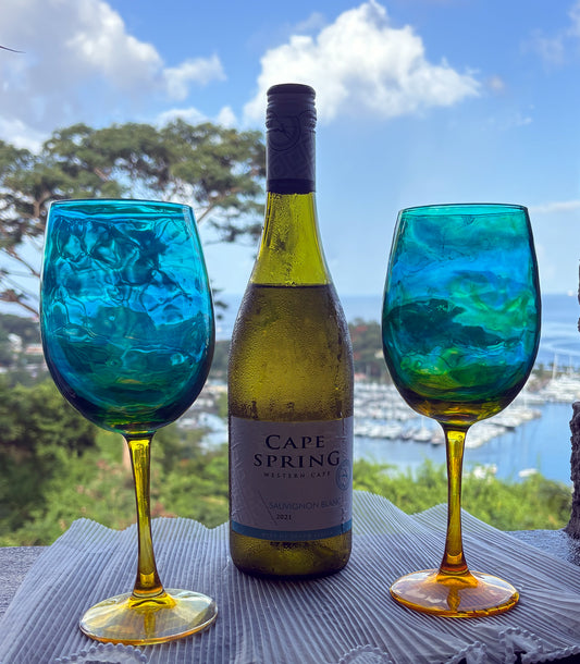 Cape Spring wine bottle with two blue and green patterned wine glasses outdoors.